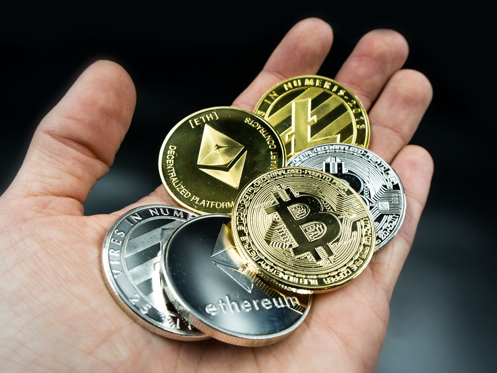 various cryptocurrency coins placed on palm of hand