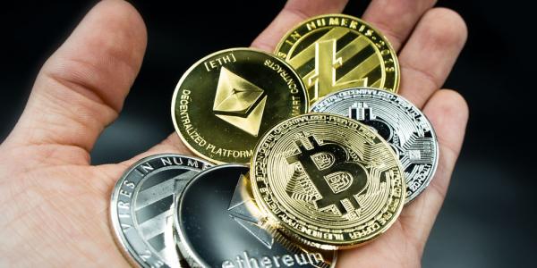 various cryptocurrency coins placed on palm of hand